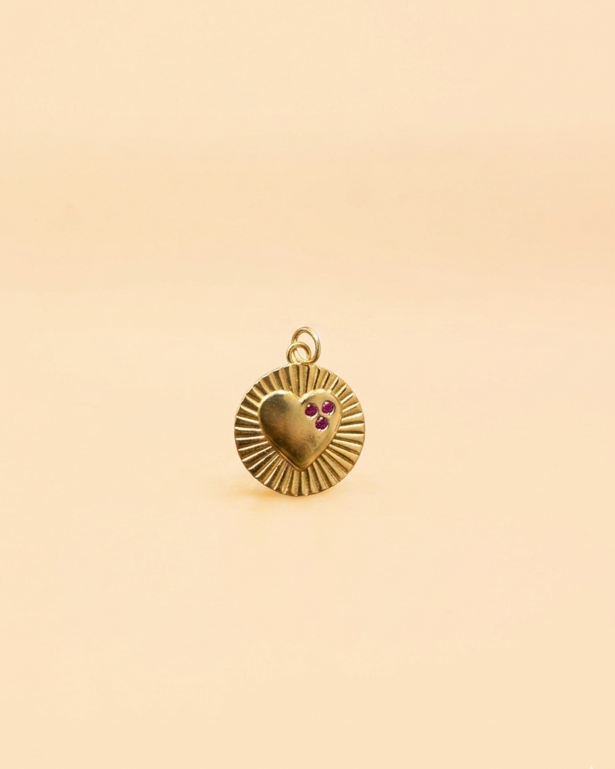 Gold pendant with a heart design on a beige background